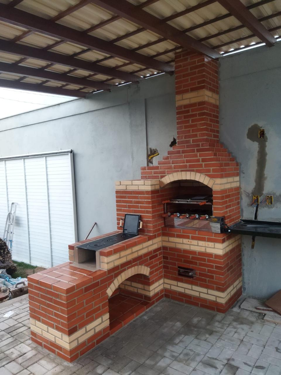 Churrasqueira de alvenaria com bancada e fogão em área gourmet