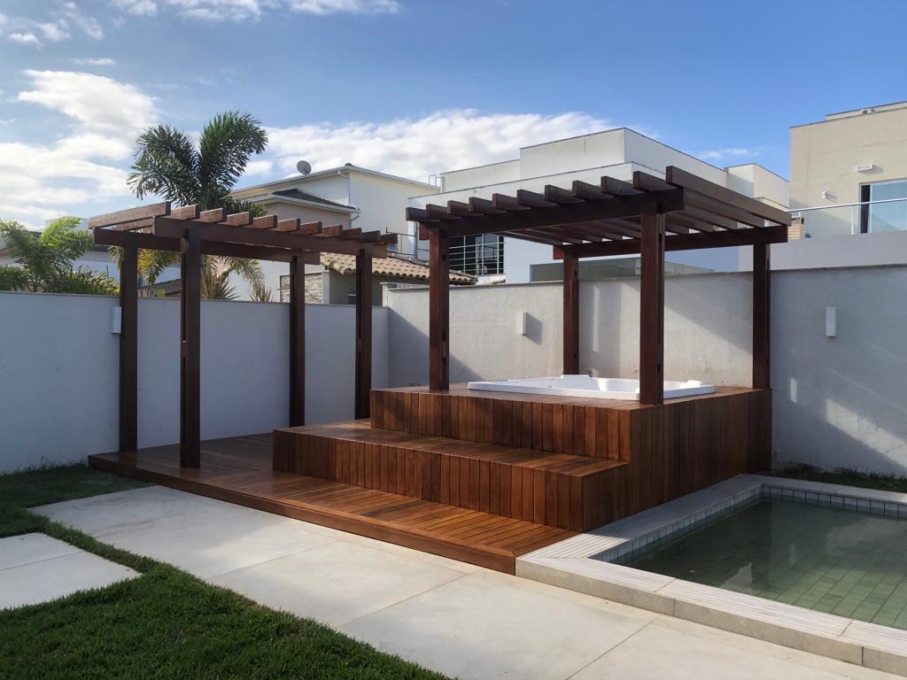 Pergolado de madeira com deck e hidromassagem ao lado da piscina